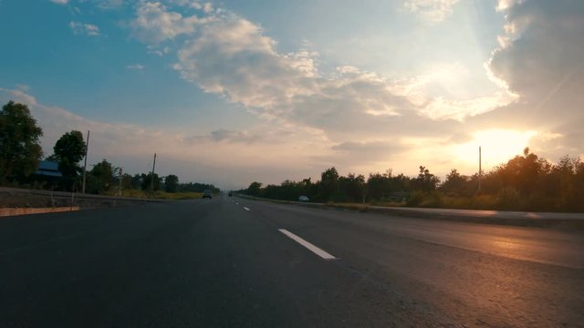POV view of car driving on the country road in the provinces of Thailand at sunrise with sunray