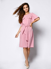 Full length portrait of happy beautiful woman in pink dress posing in studio isolated on white...