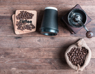 Coffee grinder,coffee beens in burlap and black paper cp on wooden table background,flat lay with copy space