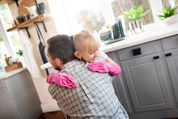 Lovely girl hugging father while cleaning kitchen together