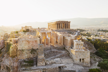 Fototapeta premium Aerial view of a slide from the drone on the panorama of residential buildings of the city of Athens, on the main symbol of ancient Greece, Acropolis at sunrise. The lights sun. World Heritage sites