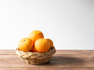 Fresh orange  fruits  set in bamboo tray on wood table with white background