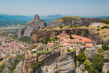 Fototapeta na wymiar Aerial view of a slide from a drone on a panorama of a mountain range. Kalampaka city, Greece. View of the cliffs of Meteora and the monasteries of Meteora. Many ancient Orthodox monasteries summer