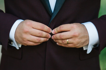 Hands of wedding groom in a white shirt dress cufflinks. Boutonni&egrave;re. groom buttoning the front of his jacket.   