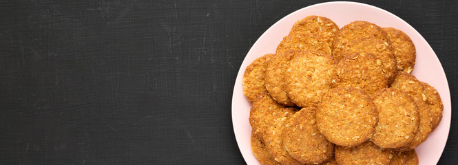 Cereal cookies on a pink plate on a black background, top view. Flat lay, overhead, from above. Copy space.