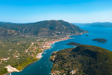 Fototapeta na wymiar Aerial view from a drone on a panorama of the blue sea, picturesque islands and mountains in Greece, in summer on a sunny day. Beautiful coastline of the resort town. Tourism