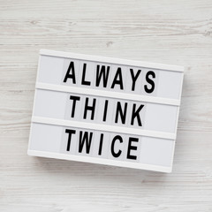 'Always think twice' words on a modern board over white wooden surface, top view. Overhead, from above. Flat lay.