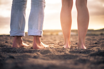 Fototapeta na wymiar Close up of nudes couple feet for romantic and romance love concept - free people barefoot on the beach looking the sunset and enjoying love couple together