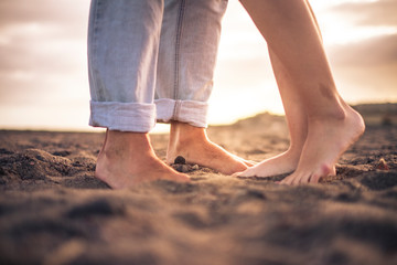 Fototapeta na wymiar Close up of nudes couple feet for romantic and romance love concept - free people barefoot on the beach looking the sunset and enjoying love couple together