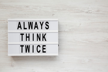'Always think twice' words on a modern board on a white wooden surface, top view. Overhead, from above, flat lay. Copy space.