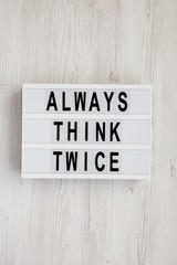 'Always think twice' words on a lightbox on a white wooden background, top view. Overhead, from...