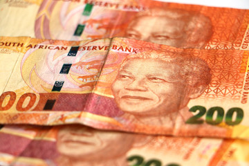A pile, stack of orange South African two hundred rand notes with Nelson Mandela's face