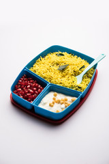 Lunch Box / Tiffin for Indian kids, contains lemon rice, nahi-boondi and pomegranate or Anar. selective focus