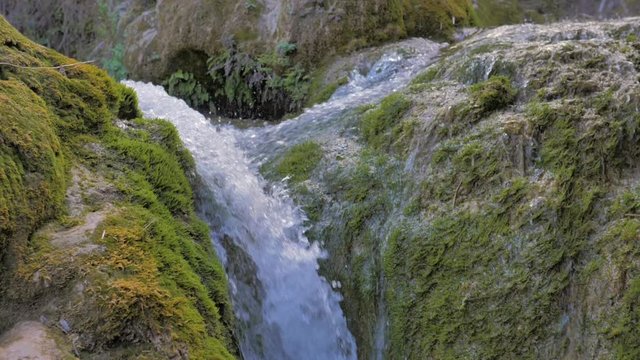 salto de agua en cascada de pequeño río de montaña sobre rocas verdes en cámara lenta