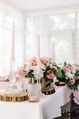 Wedding decor in gentle shades and natural materials. Pale pink candles in tall glass candlesticks