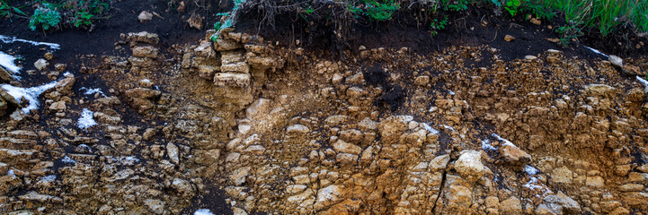 Soil cut-sandstone, stones, clay, sand structure and layers. slice of sand with layers of different structures. Layers of sedimentary sandstone rock