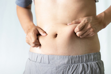 Naklejka premium Young man touching his fat belly. Fat and Health concept