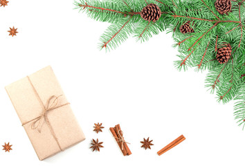 Flat lay green fluffy Christmas tree branches with pine cones, a gift in brown wrapping paper, cinnamon sticks and star anise isolated on a white background. Greeting card, banner, invitation concept