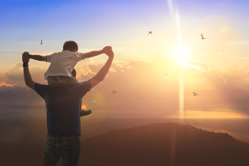 Son riding back father with outdoors on background sunset. Father holiday