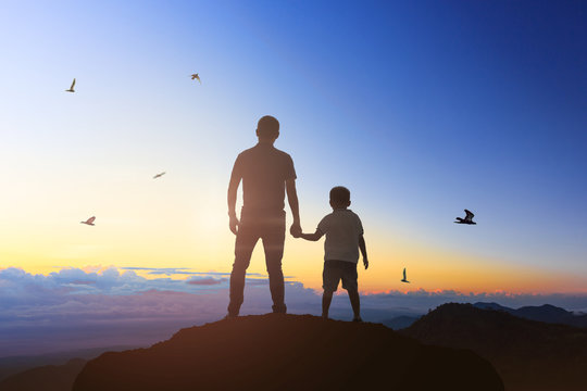Father and son holding hand in hand at the sunrise time.