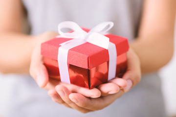 Red gift box in hand for giving  - obrazy, fototapety, plakaty