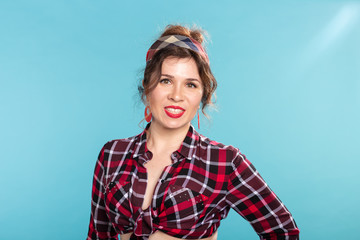 Positive beautiful young woman in a plaid vintage shirt looking at the camera and smiling posing on a blue background.