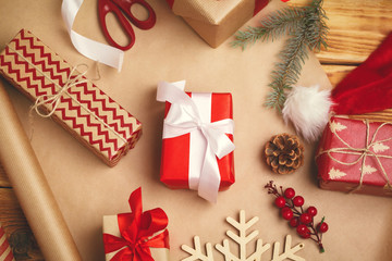 Christmas festive mood. Flat-lay of decorations, ribbons, gift paper, wrapped gift on wooden...