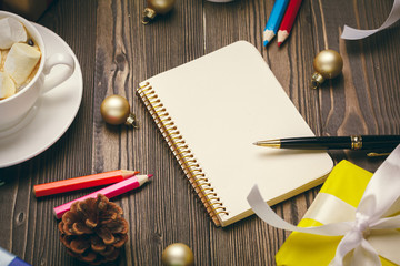 Writing christmas greeting cards. Open notepad with pen on decorated wooden table