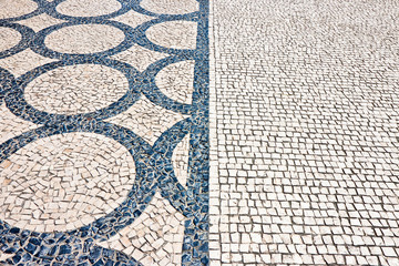 Typical portuguese floor made of small pieces of black and white stone in shape of circles and arcs (Portugal - Europe)