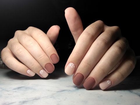 Gentle coffee manicure with white design. Short square nails with brown-beige coating and the design of twigs.