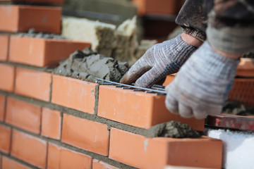 Construction site. Brick wall contruction with mason hands