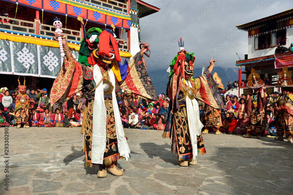 Wall mural Tawang, Arunachal Pradesh, India, Buddhist monk dancing in disguise for the Torgya  festival, in the background there are monastery and many gathered viewers.