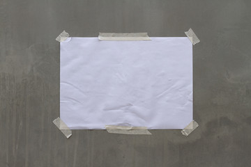 Empty old wrinkled white A4 paper stick by adhesive tape at the outdoor flat cement wall background.