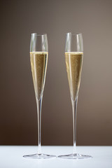 Two tall champagne flutes containing sparkling wine