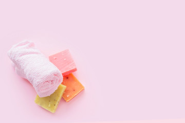 Soap and towel on pink background. Concept of natural spa cosmetics. Flat lay, top view, copy space .