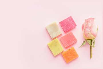 Set of soap and rose  on pink background. Concept of organic spa cosmetics. Flat lay, top view, copy space.