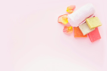 Soap, rose petals and towel on pink background. Concept of natural spa cosmetics. Flat lay, top view, copy space .