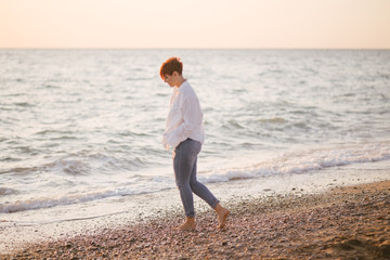 Woman with short haircut posing on beach at sunset