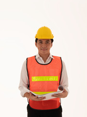 A young Asian engineer stand smiling in a white background, holding a paper, examining the work, facing straight, wearing a helmet and reflective jacket.