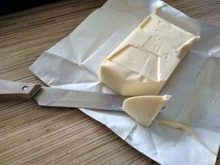 Open pack of butter with a piece that cut off the knife