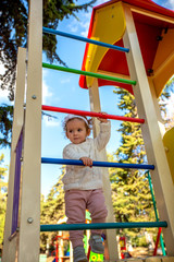 Active little girl on the playground on a multi-colored staircase.