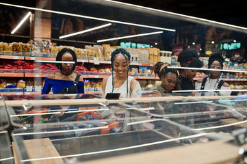 Group of five african womans with shopping carts choose rice and other groats in supermarket.