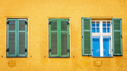Fototapeta na wymiar Windows with the green shutters and wooden stork