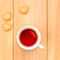 Cup of tea and sweet cookies in shape of heart on wooden background. Good morning concept.