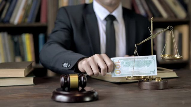 Close up Shoot of Judge Hand putting Money in Scale 