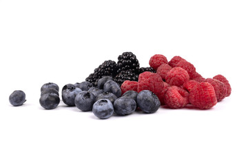 Colorful natural blueberries, blackberries and raspberries scattered randomly on white background