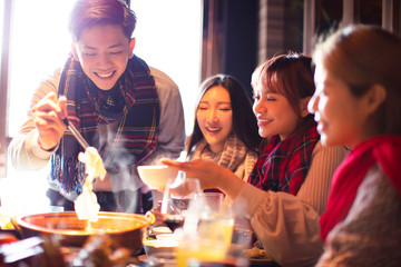 happy young friends eating hot pot in restaurant at winter - obrazy, fototapety, plakaty
