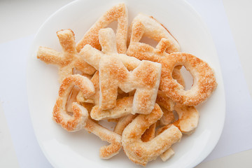 Puffs with sugar in the form of letters of the English alphabet on a plate