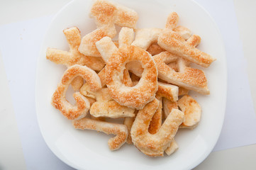 Puffs with sugar in the form of letters of the English alphabet on a plate