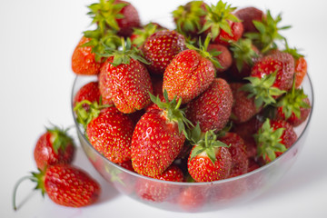 Lots of strawberries in bowl on white background.